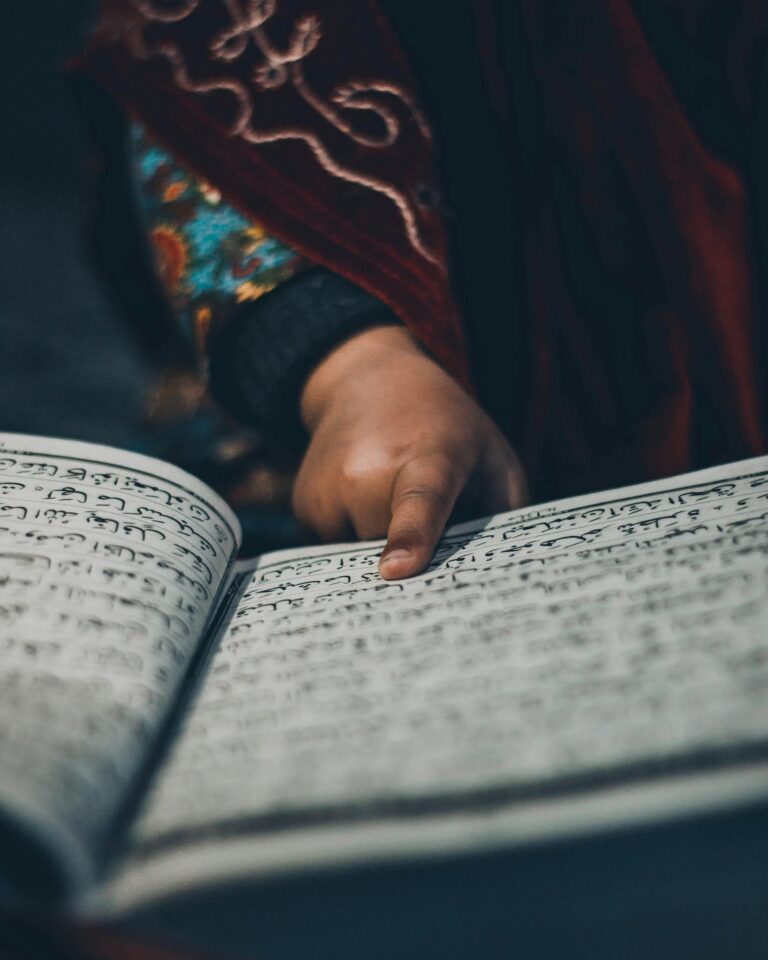 A child touching an Arabic text page, focused on reading, in Srinagar.